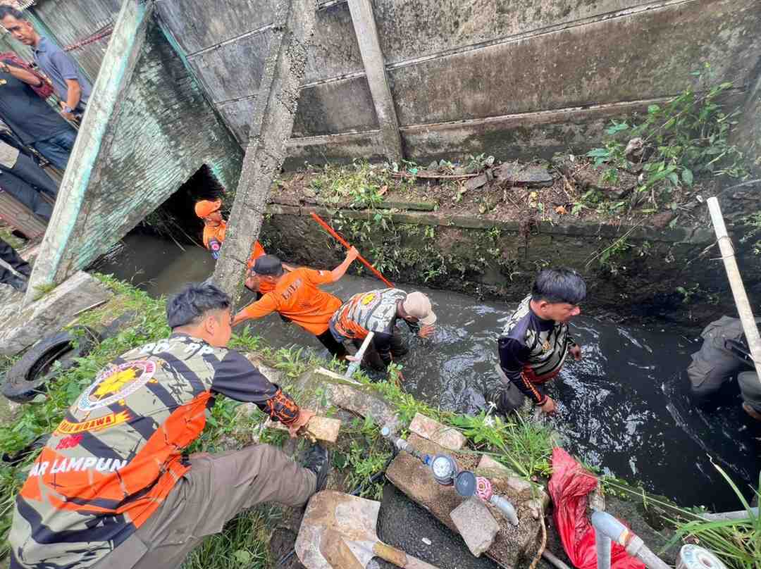Pemkot Bandar Lampung Fokus Atasi Sedimentasi, Drainase dan Sungai Langkah tersebut dilakukan melalui pembersihan drainase dan sungai yang mengalami pendangkalan akibat endapan lumpur, pasir, serta sampah. Tim Satgas Lapangan bersama aparat kecamatan melakukan pembersihan di sepanjang Jalan Pulau Singkep, Kecamatan Sukarame hingga Kecamatan Tanjungkarang Timur, pada Sabtu, 11 April 2026. Kegiatan ini difokuskan pada pengangkatan sedimen serta sampah dan tanaman liar yang menyumbat aliran air. Pembersihan dilakukan setelah terjadi luapan air di beberapa titik akibat hujan yang mengguyur wilayah tersebut sehari sebelumnya. Pemerintah kota berupaya memastikan kapasitas saluran air kembali optimal guna mencegah genangan saat hujan berikutnya. Langkah ini merupakan tindak lanjut arahan Wali Kota Bandar Lampung, Eva Dwiana, yang meminta jajarannya bergerak cepat dalam memberikan pelayanan kepada masyarakat, khususnya dalam penanganan drainase. Di lapangan, petugas gabungan dari BPBD, Dinas Lingkungan Hidup, Satpol PP, Dinas Pekerjaan Umum, serta aparat kecamatan dan kelurahan tetap bekerja meski dalam kondisi cuaca panas. Sebelumnya, Dinas Pekerjaan Umum Kota Bandar Lampung telah melakukan perbaikan saluran air dan pembersihan sedimentasi di 18 titik pada 8 April 2026. Selain itu, normalisasi sungai dan gorong-gorong juga terus dilakukan, termasuk penataan bangunan di wilayah Tanjung Senang. Sejumlah warga menyambut baik langkah cepat pemerintah kota. Mereka menilai penanganan yang dilakukan segera setelah hujan membantu mengurangi risiko banjir di lingkungan permukiman. Salah satu warga Sukarame, Reza, berharap upaya ini dapat dilakukan secara berkelanjutan dan diiringi kesadaran masyarakat untuk tidak membuang sampah sembarangan. Wali Kota Eva Dwiana menegaskan, normalisasi sungai dan pembersihan sedimen menjadi prioritas utama sebagai solusi jangka panjang untuk mengatasi persoalan banjir di Kota Bandar Lampung. (***)