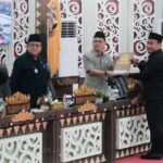 Ranperda APBD Bandar Lampung Dibahas, Deddy Sampaikan Jawaban Wali Kota Jawaban Wali Kota Bandar Lampung disampaikan Wakil Wali Kota Deddy Amarullah dalam Sidang Paripurna Pembicaraan Tingkat I DPRD Kota Bandar Lampung di Ruang Sidang Paripurna DPRD, Kamis (17/9/2026). Dalam paripurna tersebut, Deddy menyampaikan tanggapan pemerintah kota terhadap sejumlah masukan, saran dan pertanyaan yang sebelumnya disampaikan fraksi-fraksi DPRD terkait Ranperda APBD. Penyampaian jawaban tersebut menjadi bagian dari rangkaian pembahasan rancangan anggaran daerah sebelum memasuki tahapan berikutnya. Pemkot Bandar Lampung menyatakan berbagai pandangan yang disampaikan fraksi DPRD menjadi bahan dalam penyempurnaan rancangan kebijakan anggaran. Pembahasan mencakup arah program pembangunan dan kebutuhan pelayanan masyarakat yang akan dituangkan dalam APBD. Pemerintah kota juga menegaskan pembahasan anggaran dilakukan dengan mengedepankan transparansi dan akuntabilitas. Sidang paripurna dihadiri pimpinan dan anggota DPRD Kota Bandar Lampung serta jajaran organisasi perangkat daerah (OPD) di lingkungan Pemerintah Kota Bandar Lampung. Setelah jawaban pemerintah daerah disampaikan, pembahasan Ranperda APBD akan dilanjutkan melalui tahapan yang telah ditetapkan hingga nantinya menjadi APBD Kota Bandar Lampung.